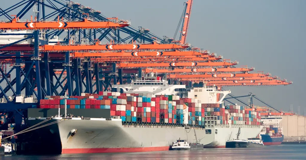 Containerschiff im Hafen von Rotterdam beim Beladen mit großen Kränen und gestapelten Containern